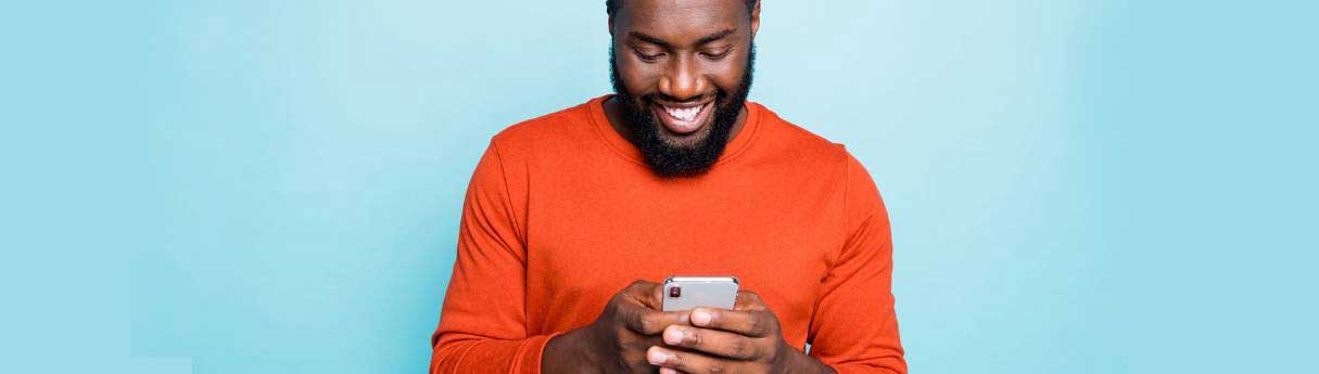 Man in orange sweater smiles while using ICC's Incoterms 2020 app
